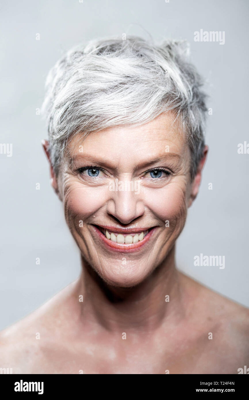 Portrait of laughing mature woman with short grey hair and blue eyes Stock Photo