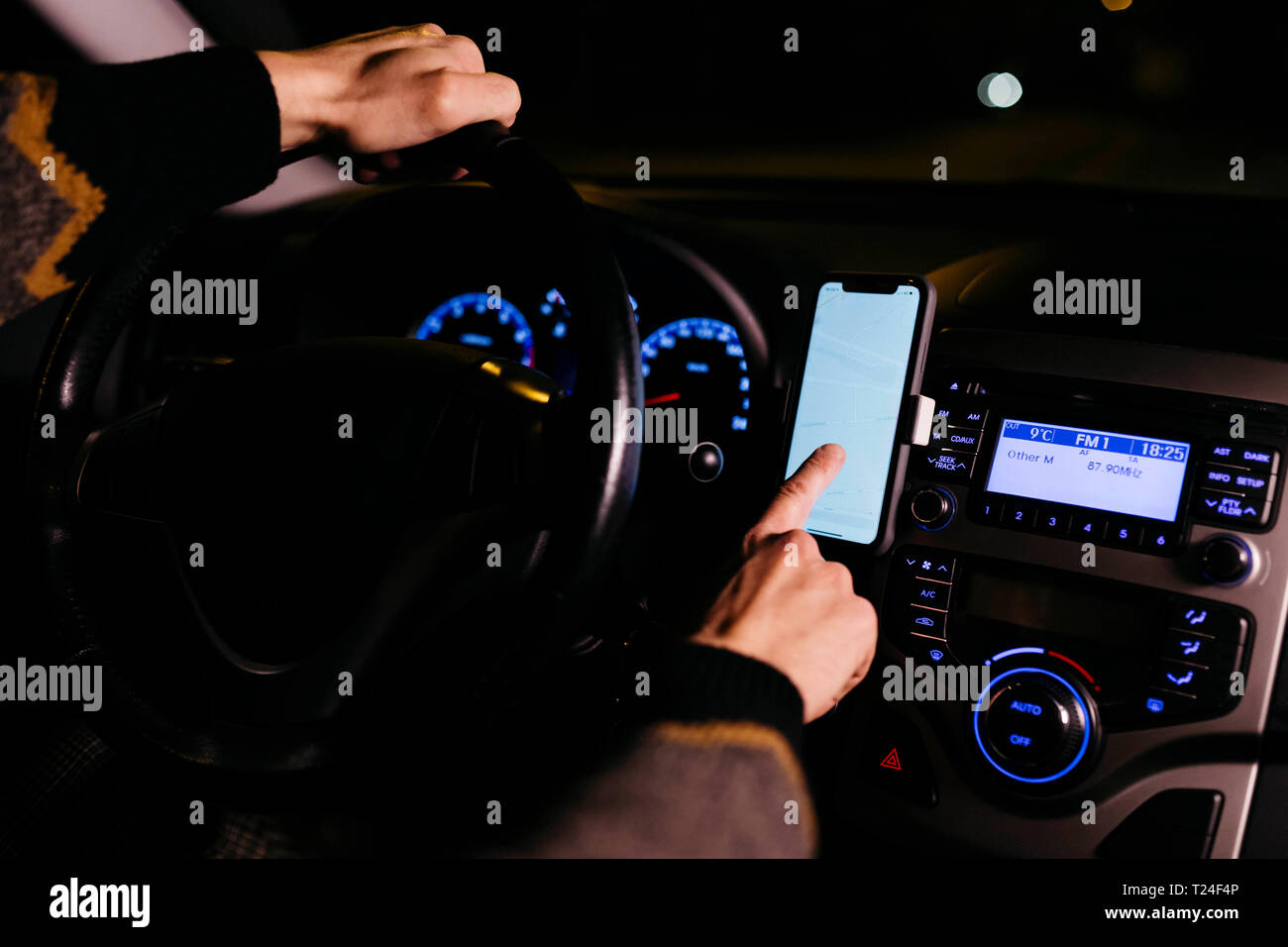 Man using cell phone with road maps in the car at night Stock Photo
