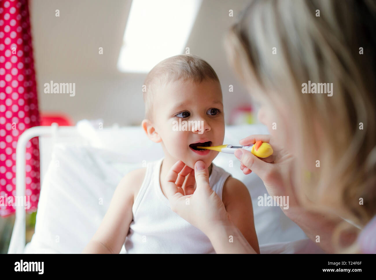 Mother taking temperature of toddler son at home Stock Photo