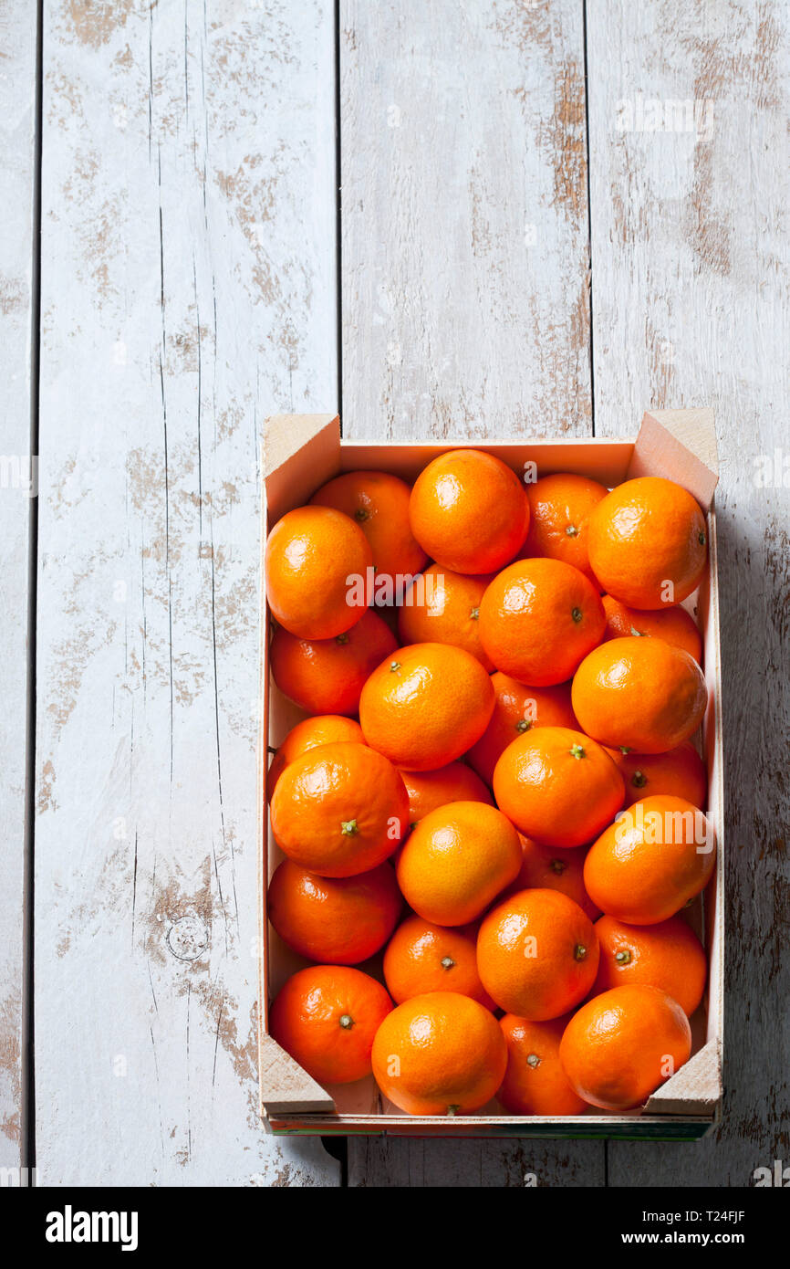 Tangerines in crate, on white, wooden background Stock Photo