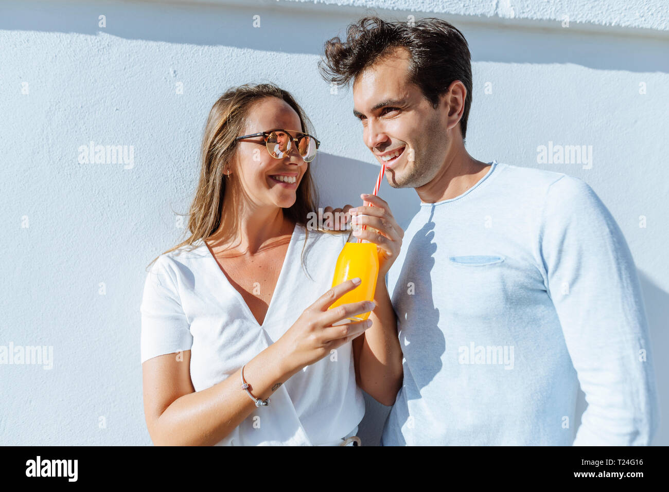 Happy couple sharing an orange juice on a sunny day Stock Photo