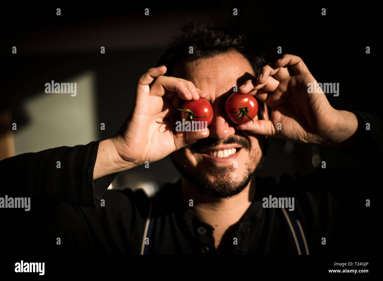 Man covering his eyes with tomatoes Stock Photo