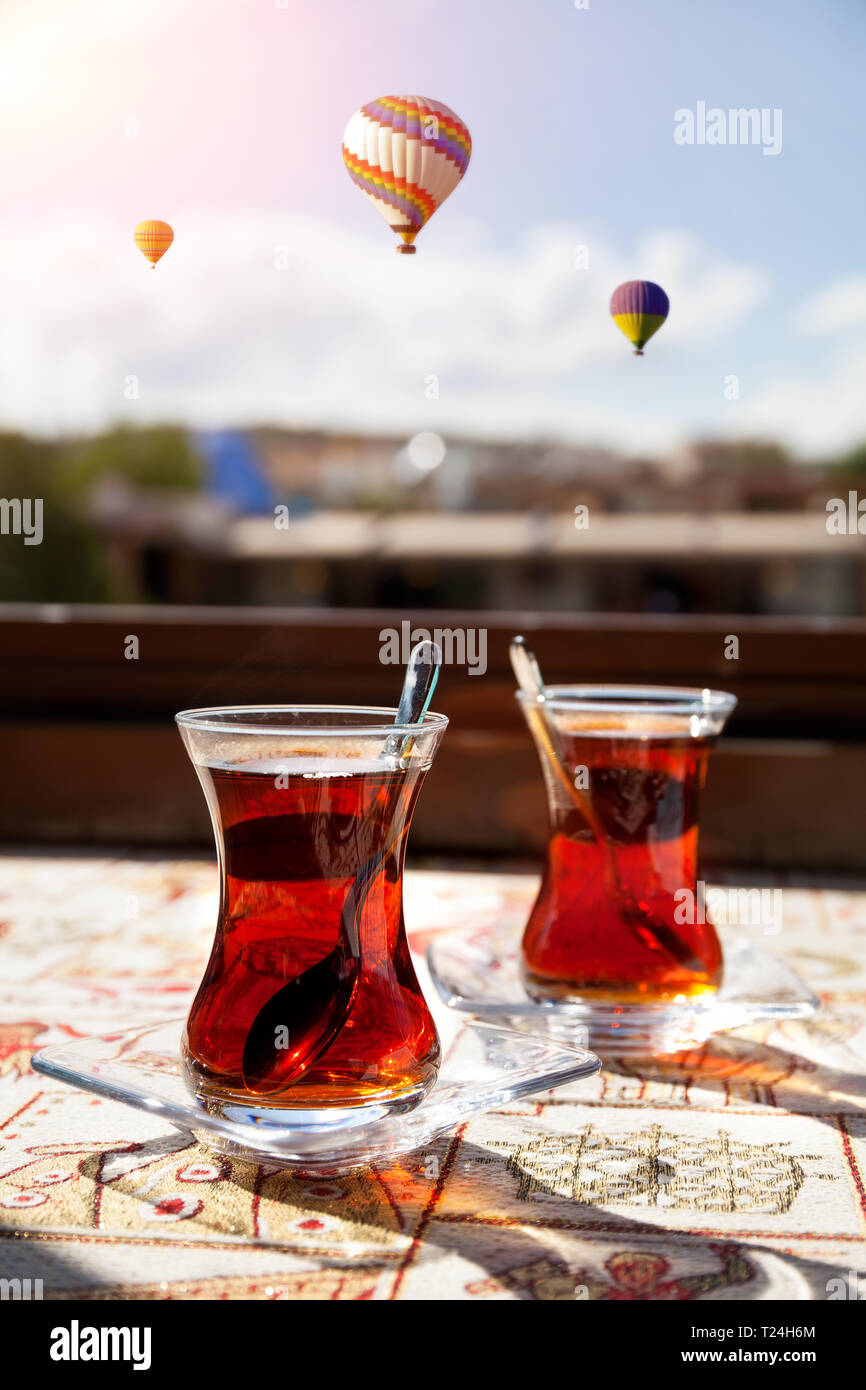 Turkish tea in restaurant and hot air balloon fly over blue sky in
