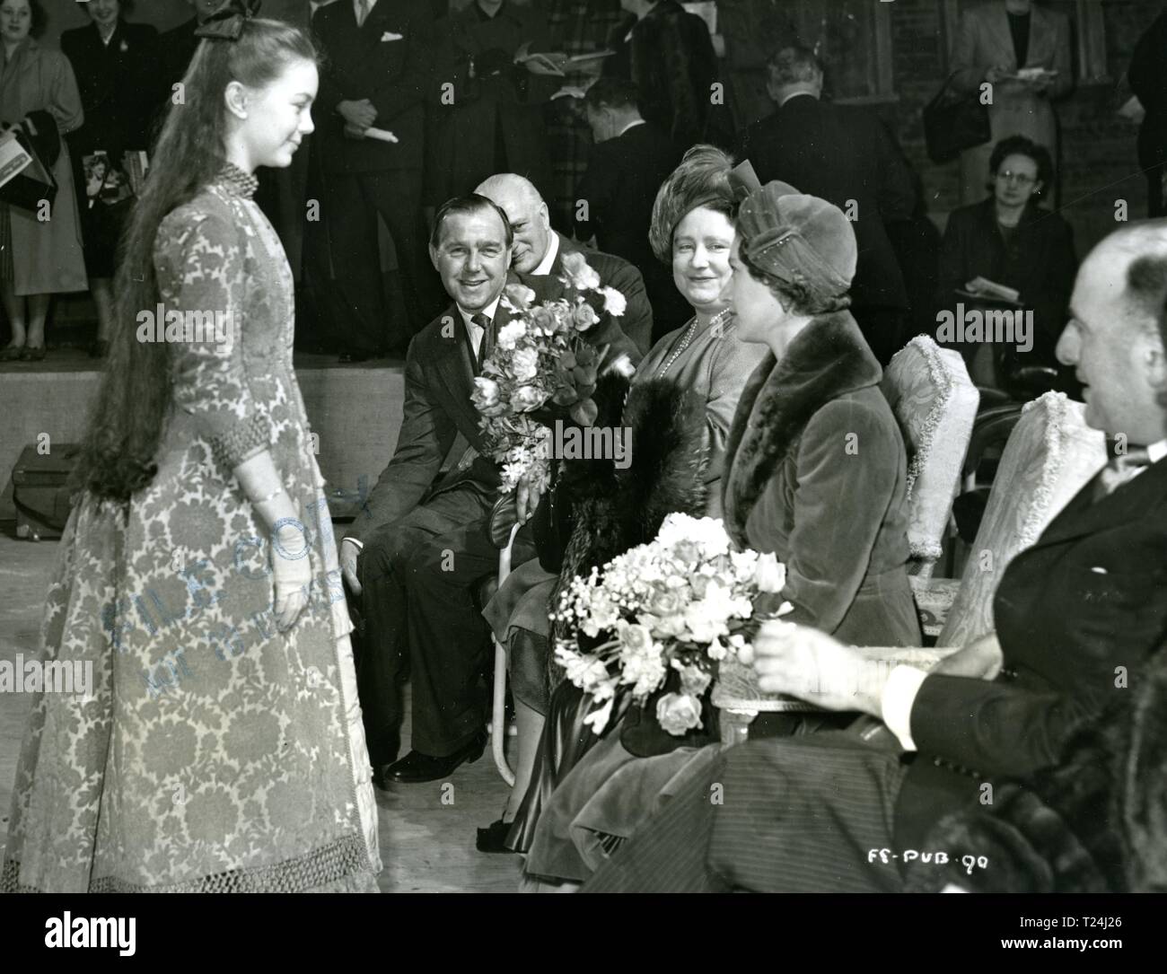 Queen Elizabeth (later the Queen Mother) and Princess Margaret on the set of the Magic Box presented with flowers by Janette Scott at Ealing Studios in 1951      Date: 1951 Stock Photo