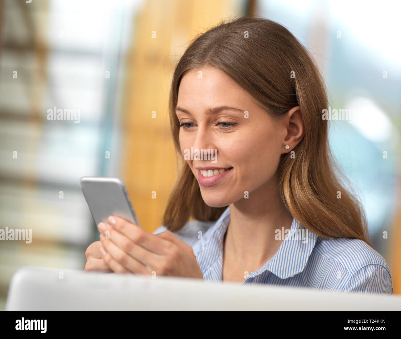 Smiling businesswoman using cell phone in office Stock Photo