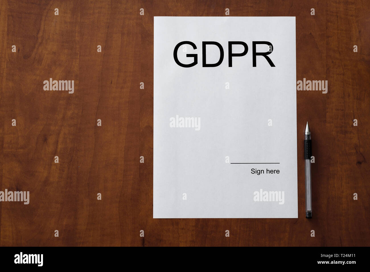 White sheet of paper on wooden table with pen. Blank space on the paper with empty place to sign it with GDPR word. General Data Protection Regulation Stock Photo