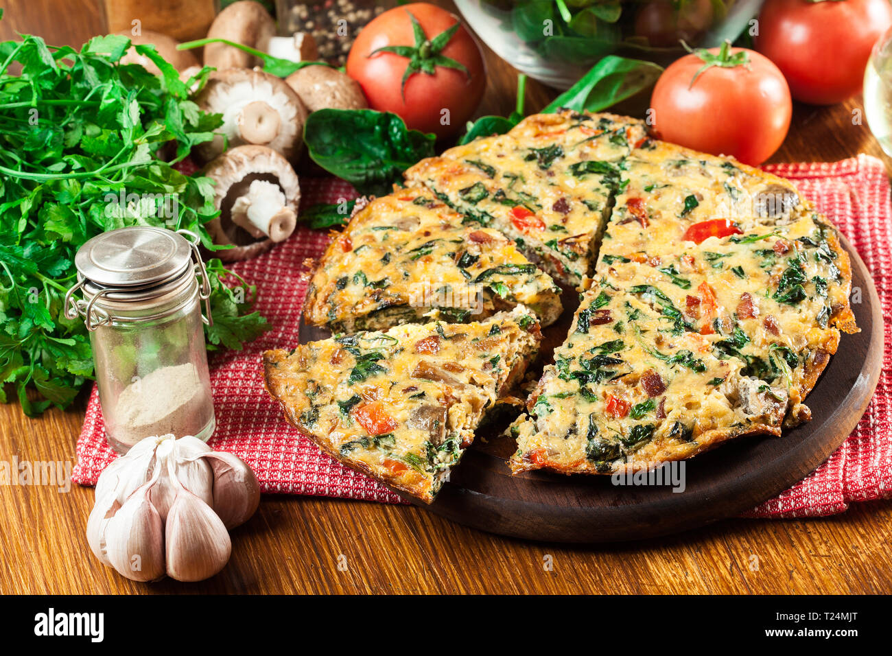 Frittata made of eggs, mushrooms and spinach on a cutting board. Italian cuisine Stock Photo