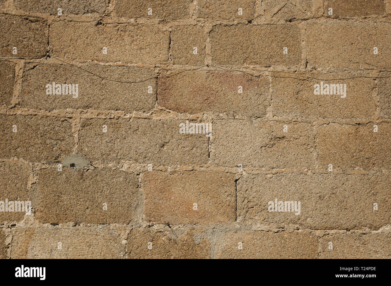Old wall made of large stone bricks, forming a charming pattern at
