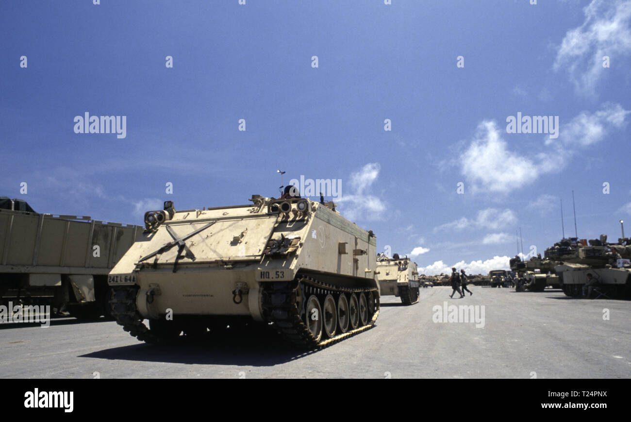 30th October 1993 U.S. Army United Defense M113 APCs of the 24th Infantry Division, 1st Battalion of the 64th Armored Regiment in the new port in Mogadishu, Somalia where they have just arrived by sea. On the right, tank crews relax in the shade of their M1A1 Abrams tanks, also arrived early that morning. Stock Photo