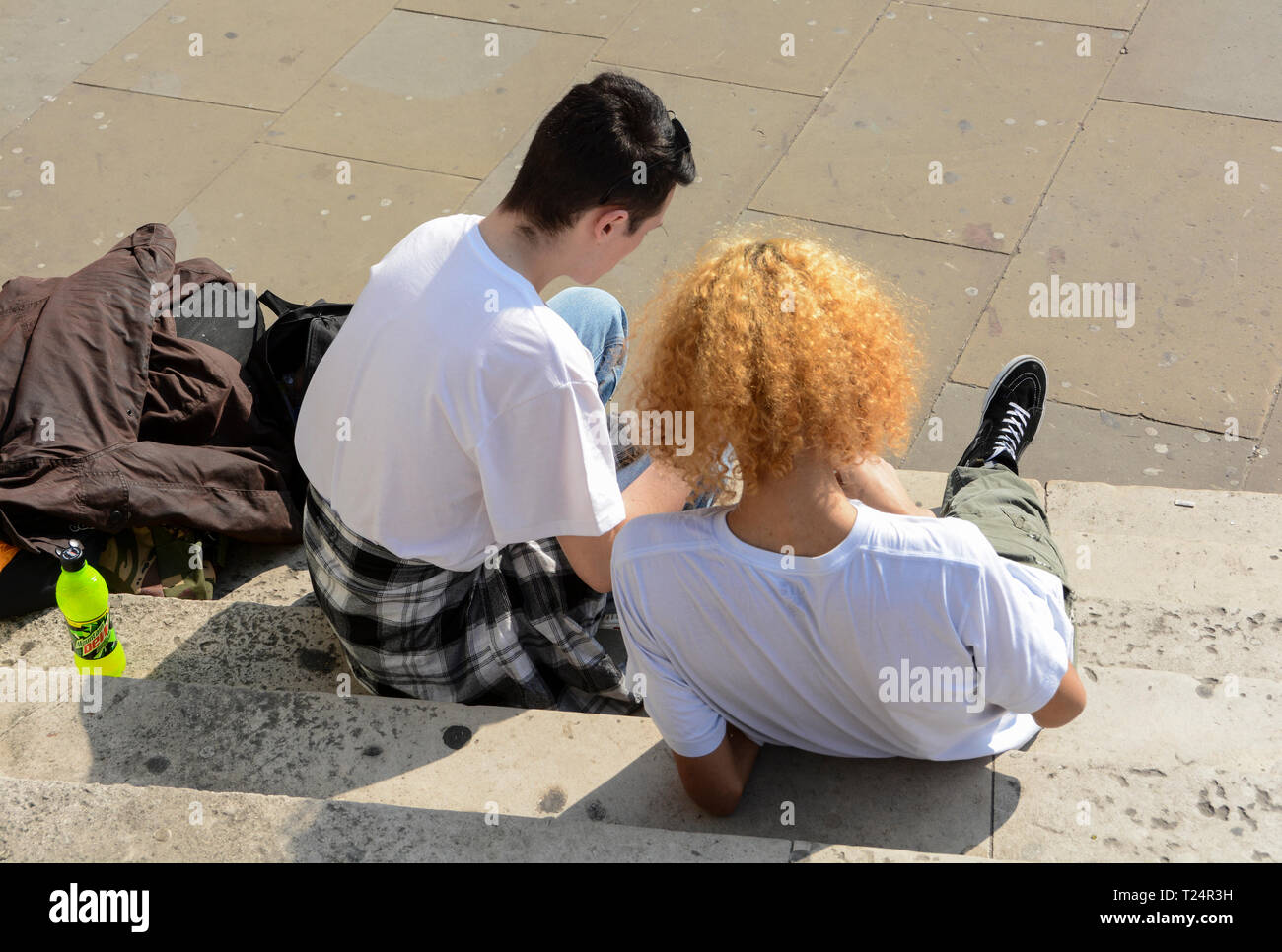 Two young men sitting on steps near London Bridge chilling the day away Stock Photo