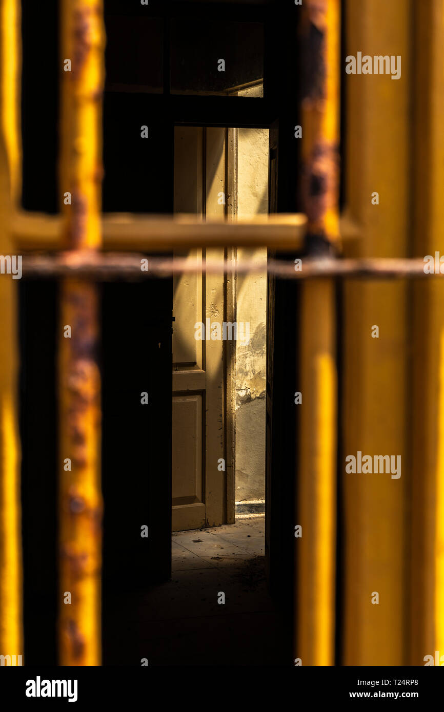 View through metal bars to the interior room with open door and shaft of light shining in the old lighthouse building in the Malpais de la Rasca, Palm Stock Photo