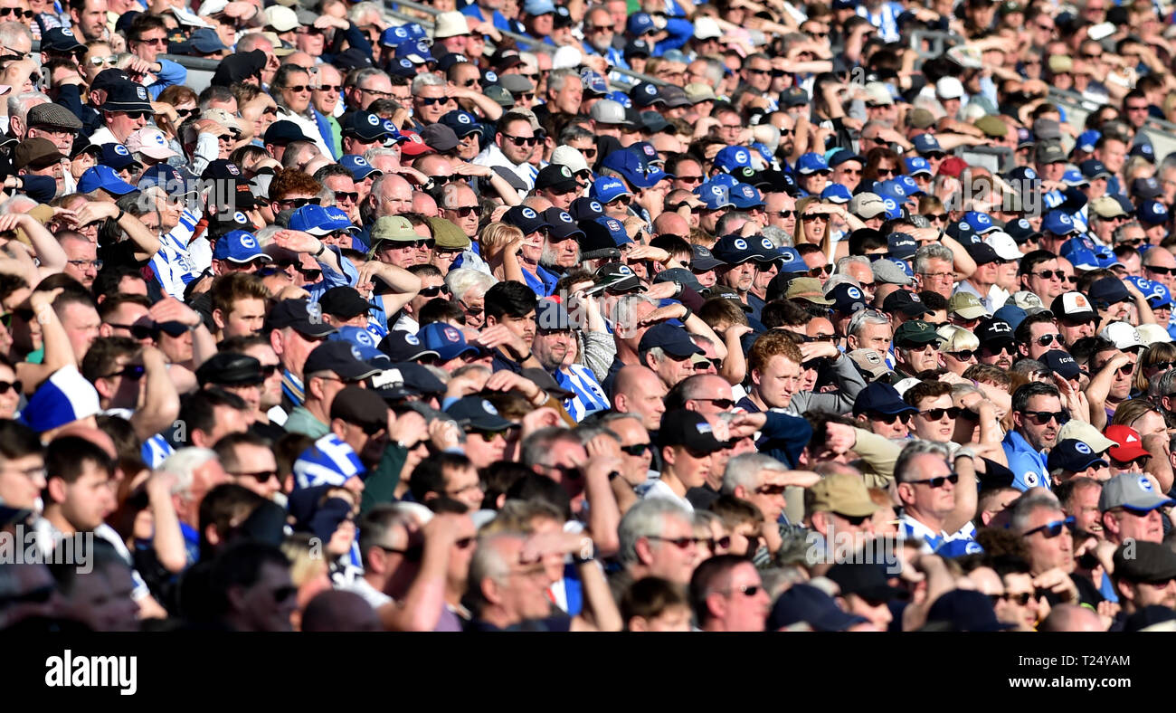 Fans shield their eyes in the sun during the Premier League match between Brighton & Hove Albion and Southampton at The American Express Community Stadium . 30 March 2019 Editorial use only. No merchandising. For Football images FA and Premier League restrictions apply inc. no internet/mobile usage without FAPL license - for details contact Football Dataco Stock Photo