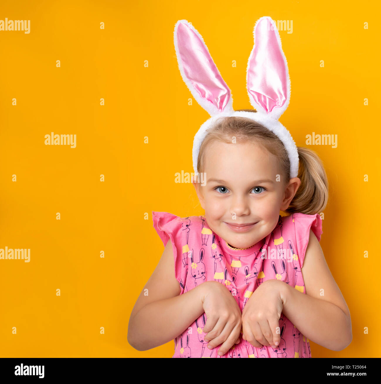 Beautiful cute little girl dressed in Easter bunny ears on a yellow