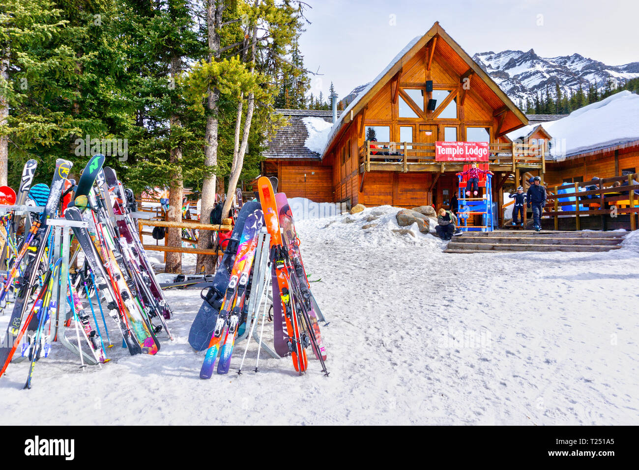 LAKE LOUISE, CANADA - MAR 23, 2019: Colorful skis and snowboads line the rack outside the old and rustic Temple Lodge at Lake Louise in the back mount Stock Photo