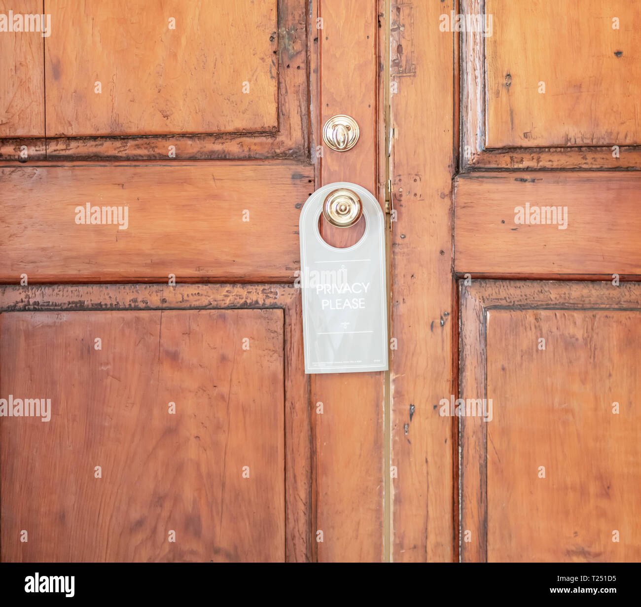 old wooden paneled door with a do no distrub sign hanging from the door knob. Stock Photo