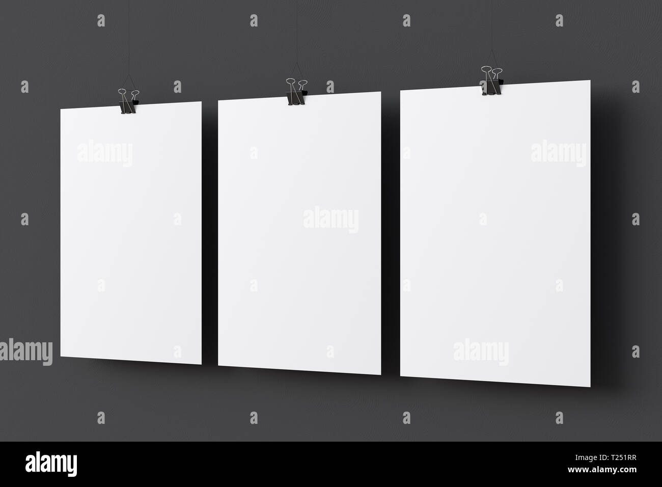 Three blank paper posters hanging on binder clips on black wall