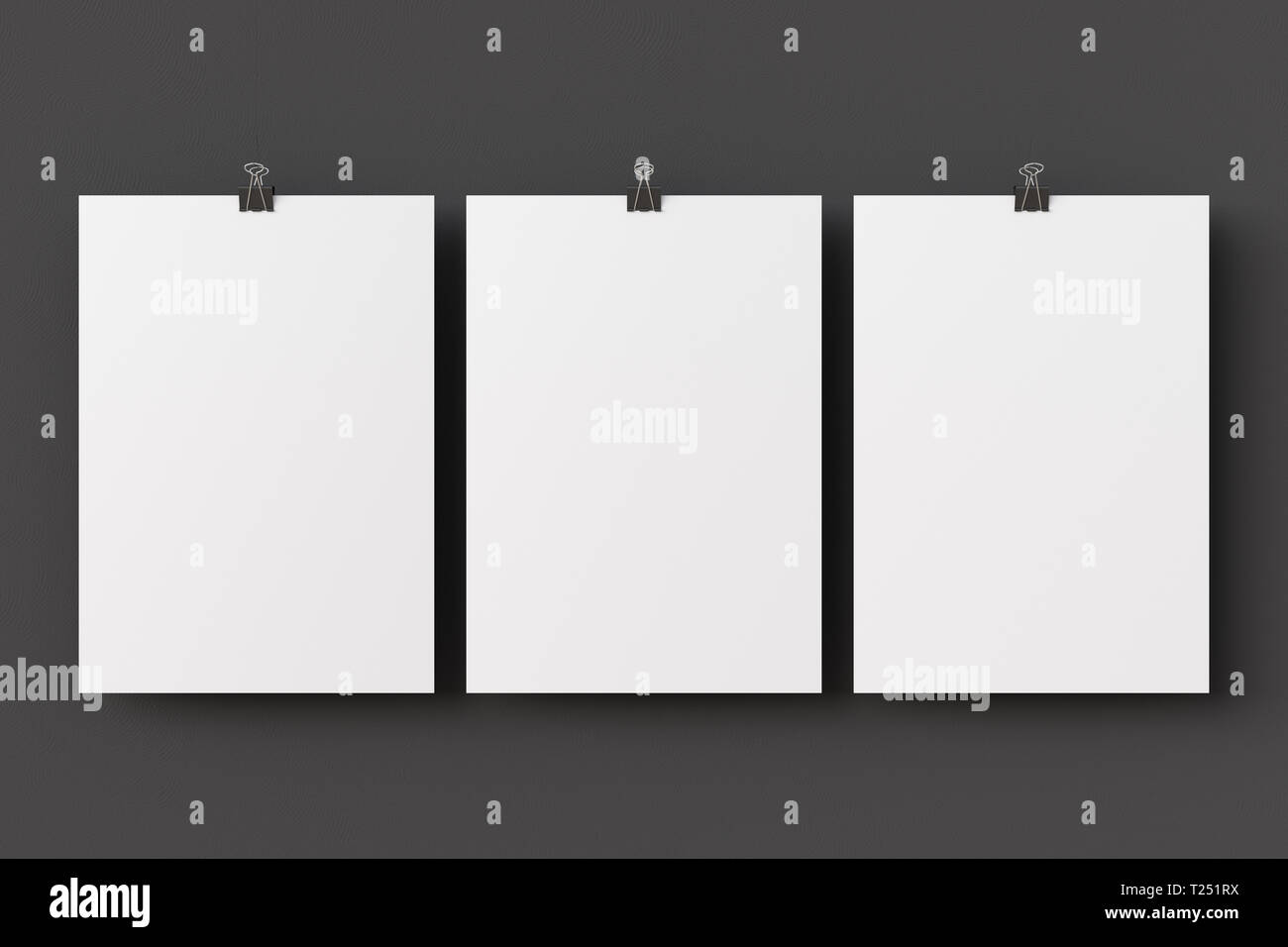 Three blank paper posters hanging on binder clips on black wall