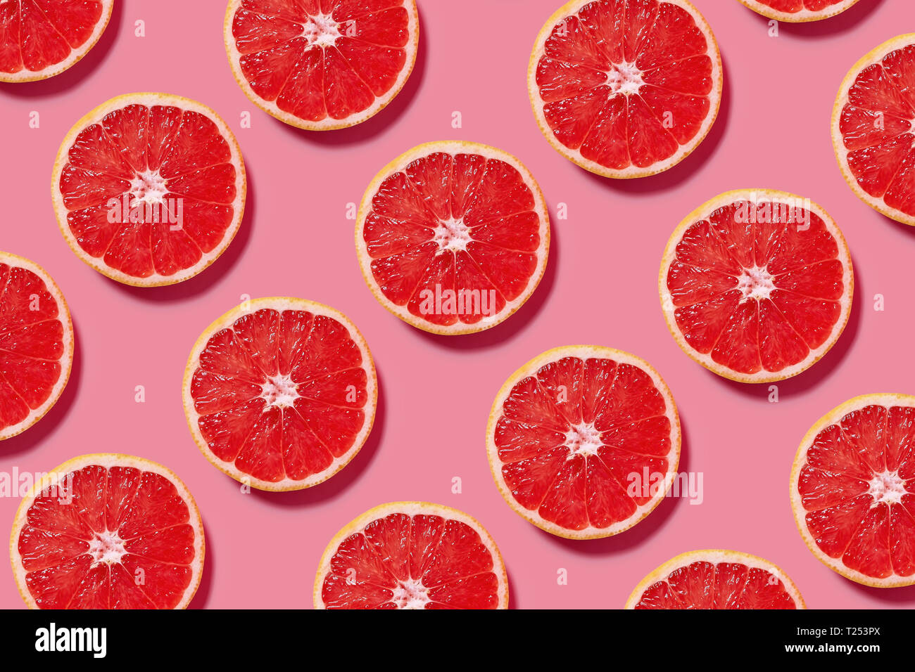 Colorful fruit pattern of fresh grapefruit slices on pink background. Minimal flat lay concept. Stock Photo