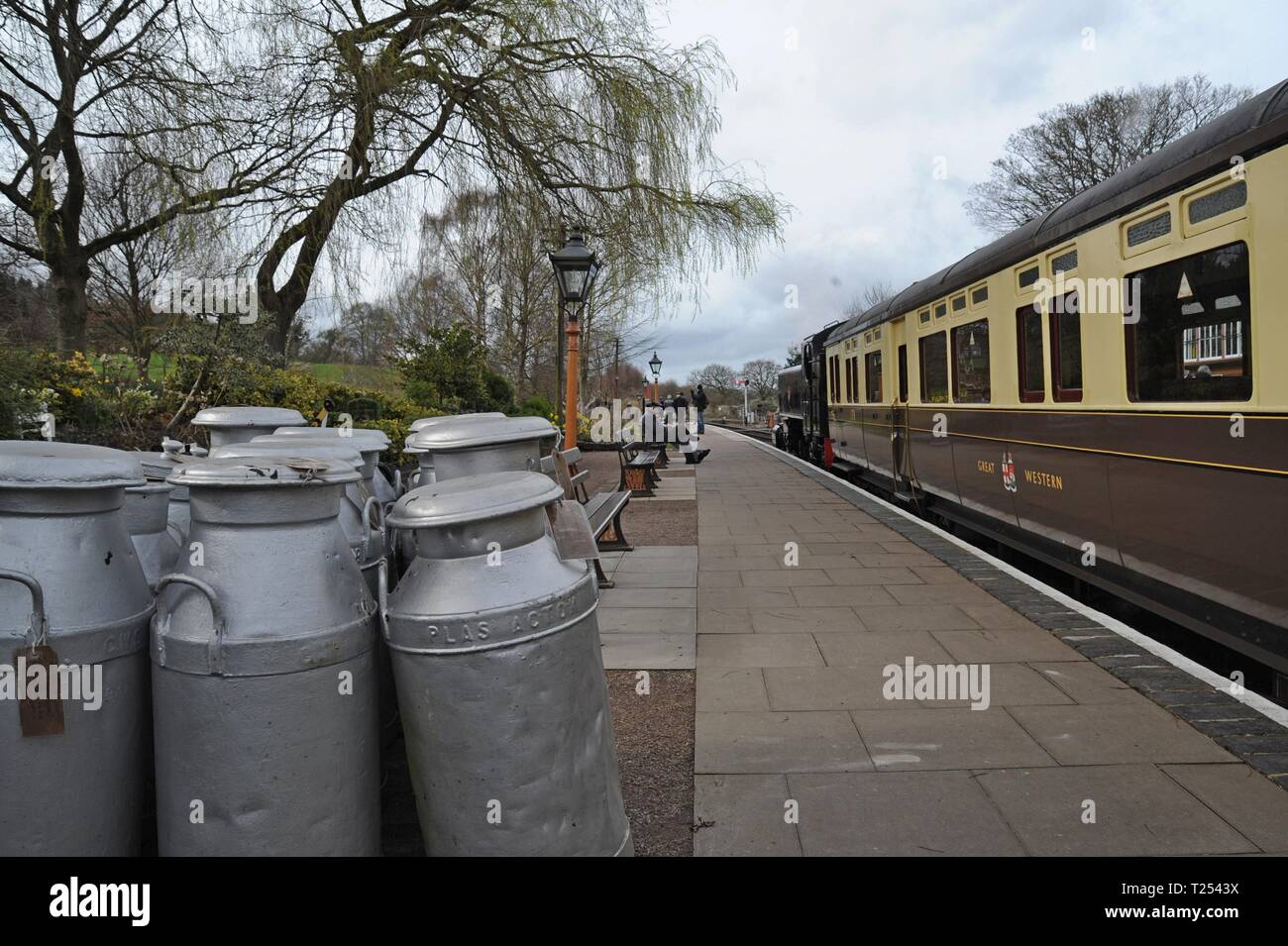 A train waits next to a trolley carrying restored vintage milk churns