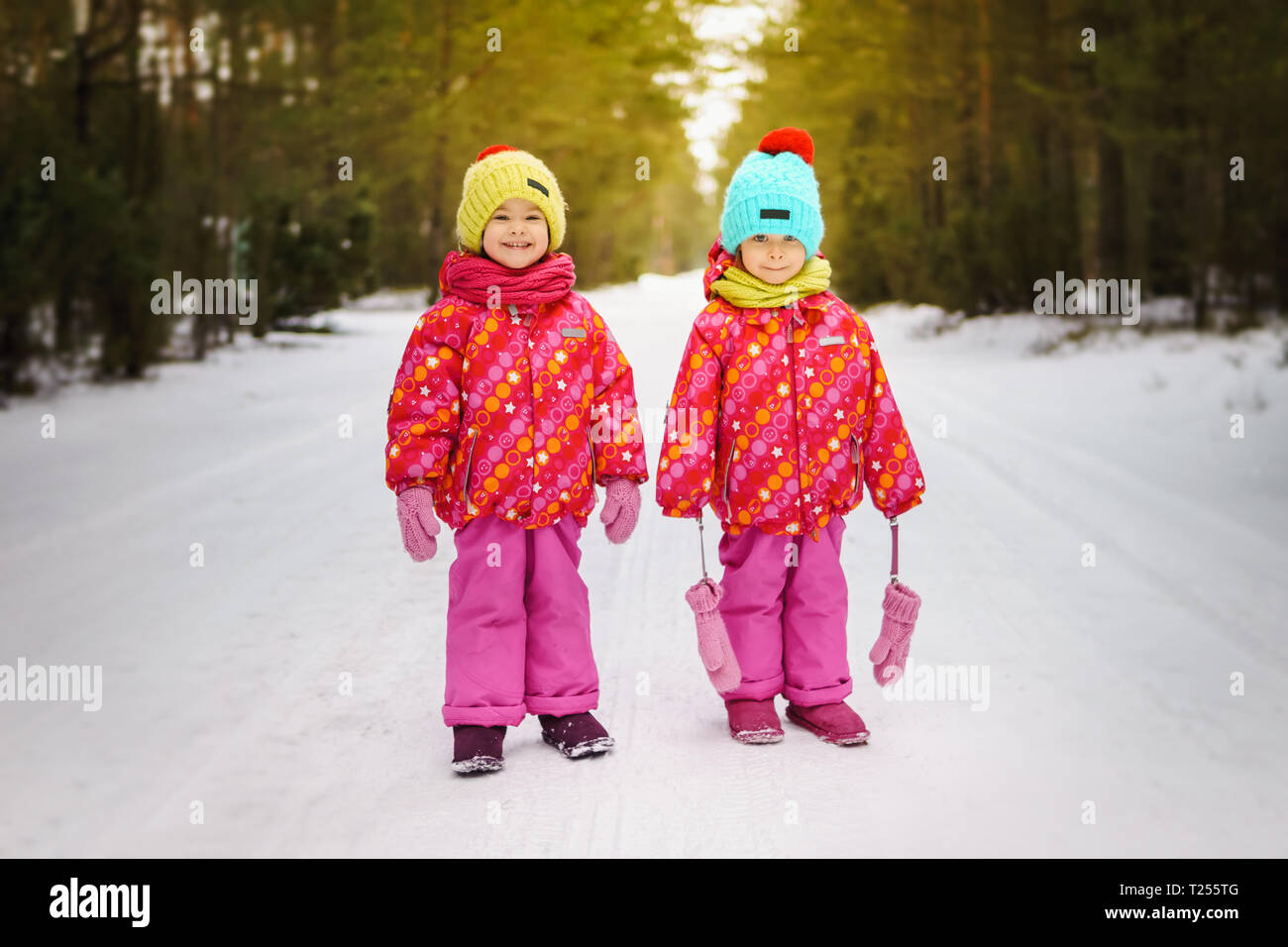 Two girls are standing on snowy road in the woods Stock Photo - Alamy