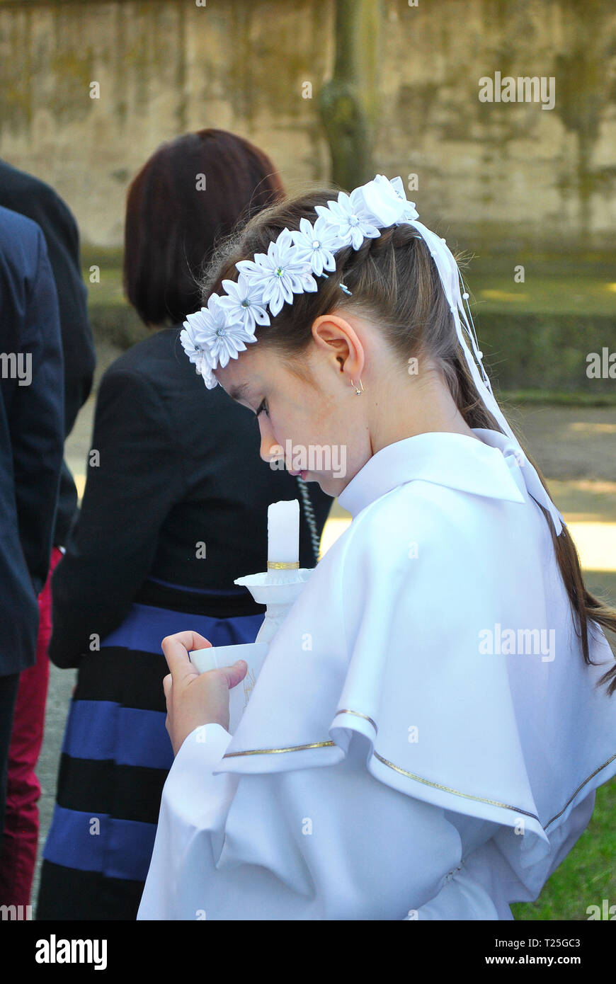 Poznan - Poland / May 22 2016, Young girl in white alba clothing is waiting  amongst guests outside the Church on a day of her First Holy Communion  Stock Photo - Alamy