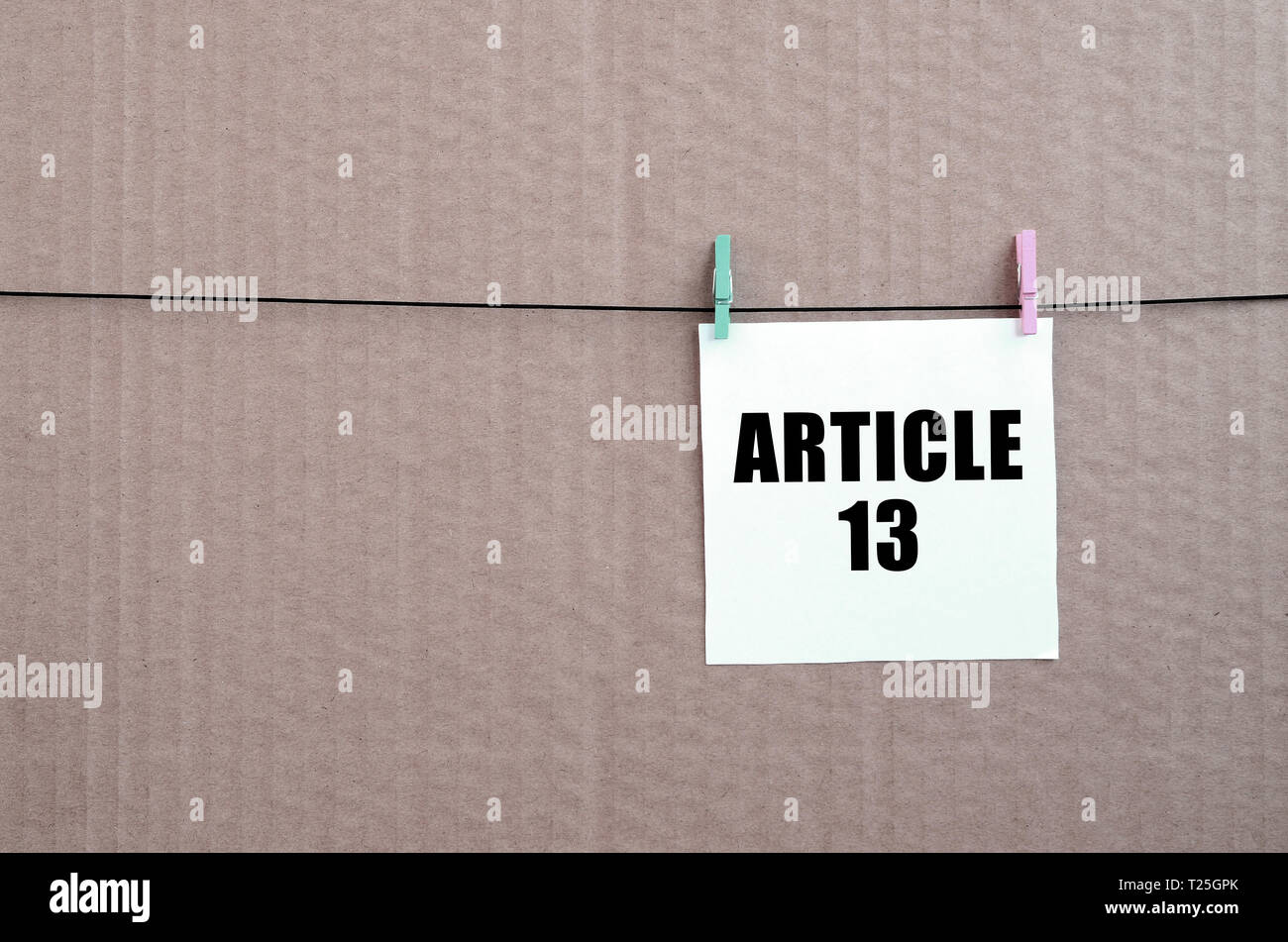 Article 13 inscription on white card on rope on a brown cardboard background. European copyright directive including article 13 is approved by europea Stock Photo