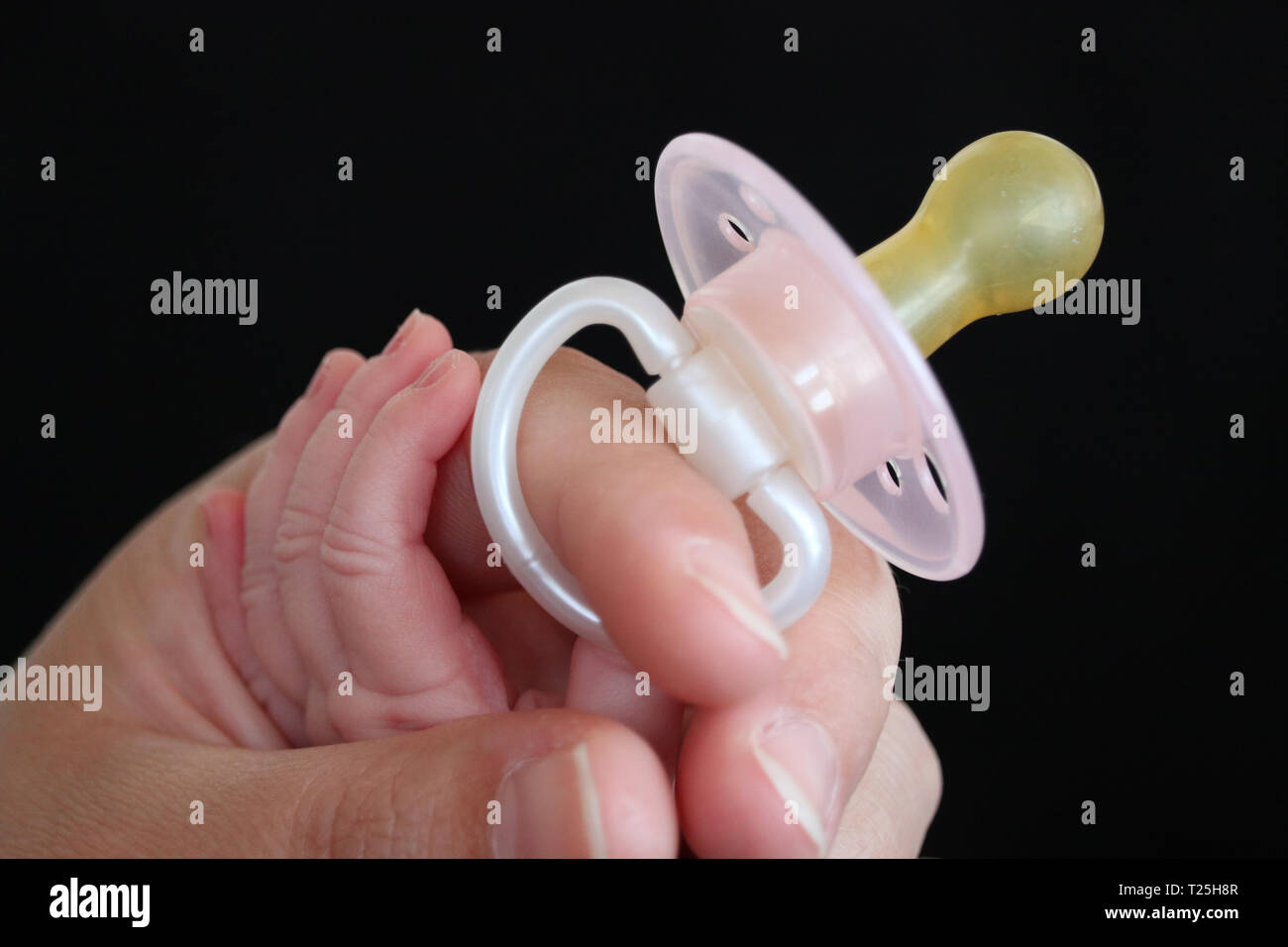 Baby hand is grabbing for pacifier in mum´s hand Stock Photo - Alamy
