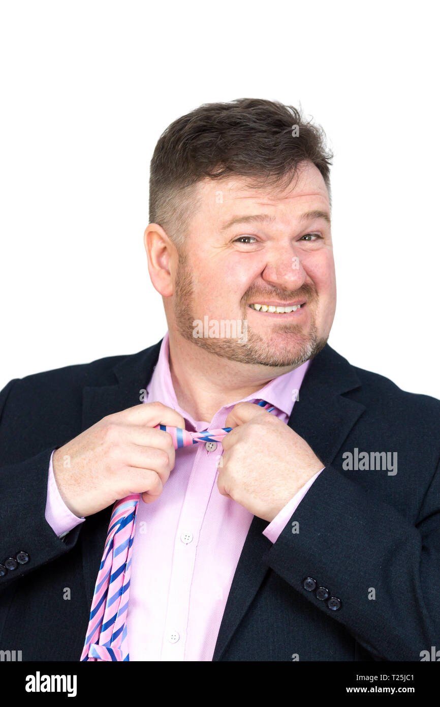 Angry fat man with a beard stretches removes his tie from his neck Stock Photo