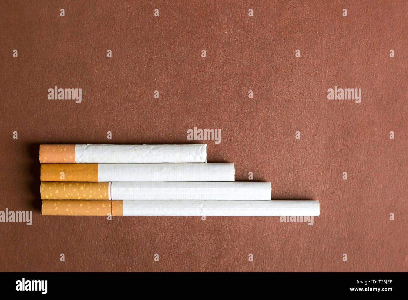 Cigarettes of tobacco with a filter of different sizes in length on a brown  background Stock Photo - Alamy