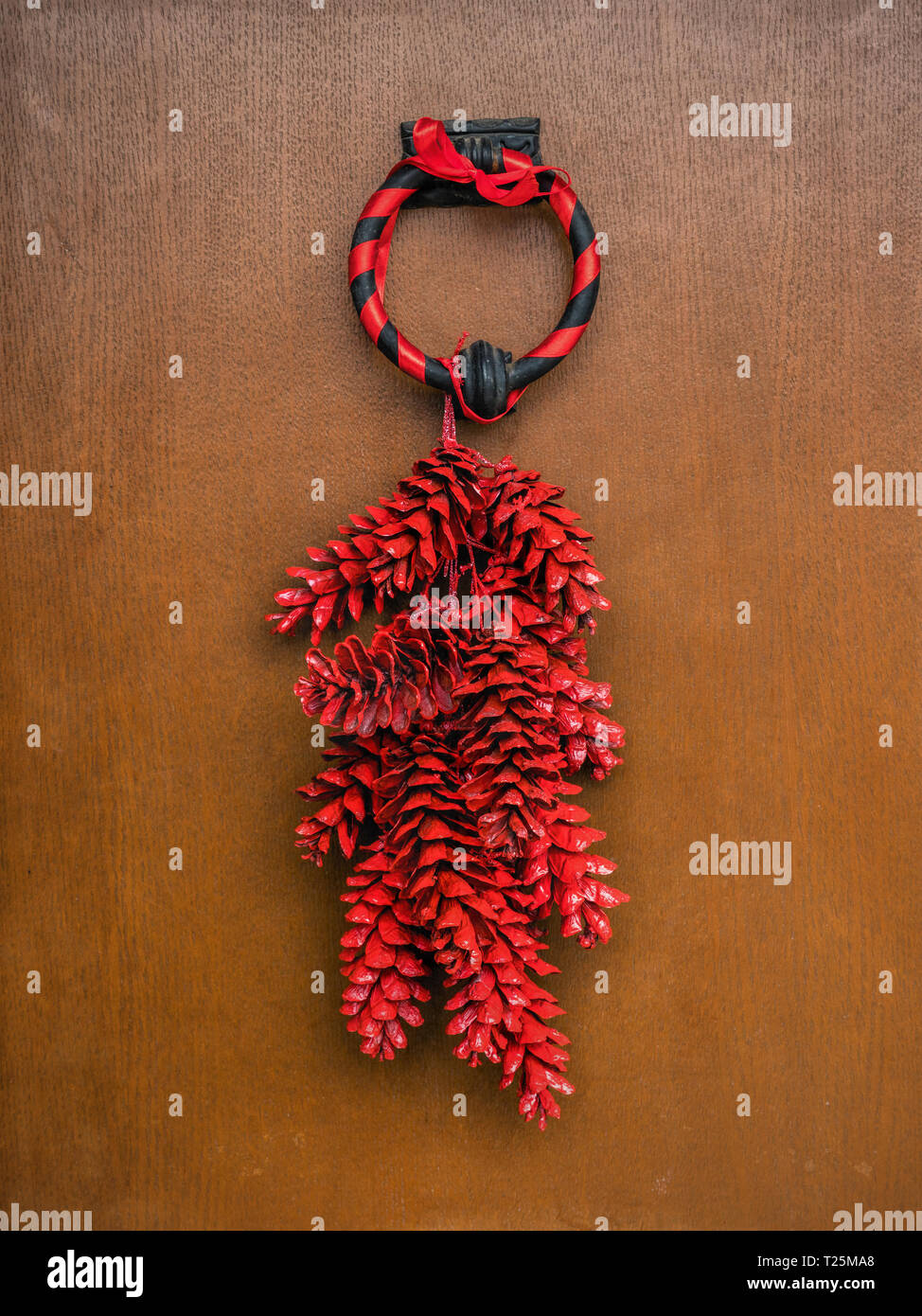 Red pinecone Christmas wreath attached to the wooden door Stock Photo
