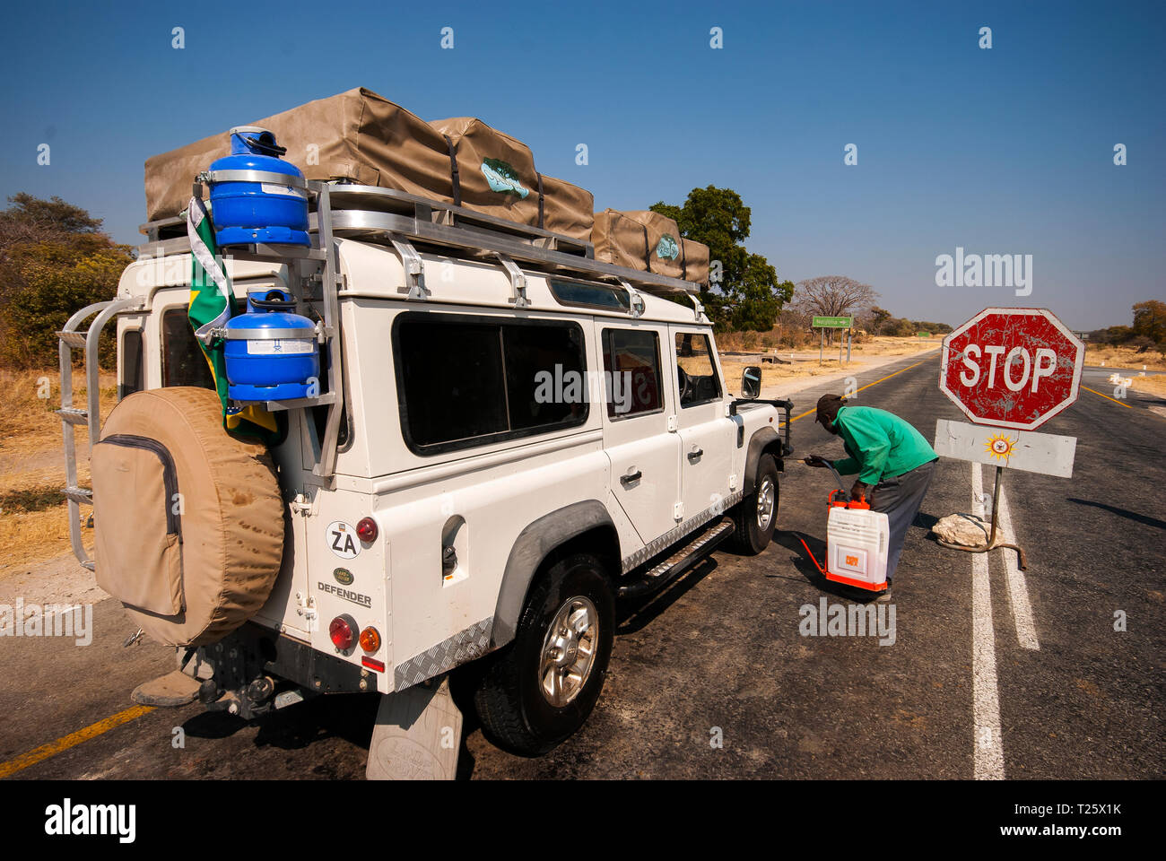 African man sprinkling a product in a Land Rover jeep as a prevention of cattle disease Stock Photo