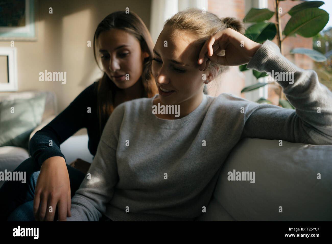 Two teenage girls sitting on couch at home Stock Photo - Alamy