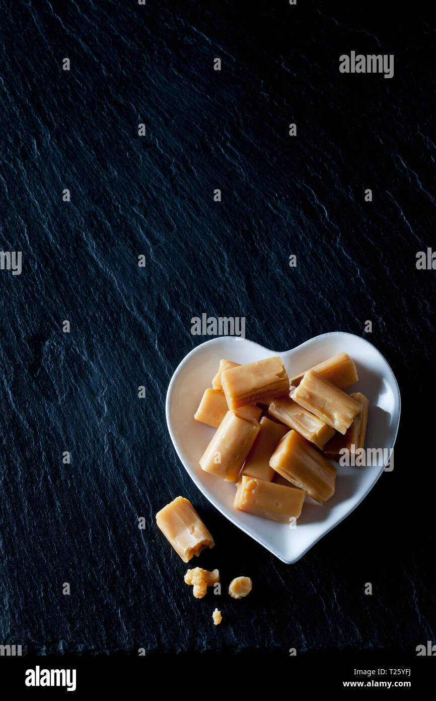 Cream toffees on a heart-shaped plate Stock Photo