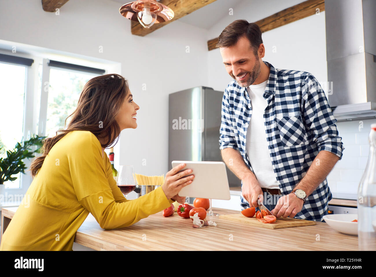 Affectionate couple in kitchen, preparing spaghetti toghether, using digital tablet Stock Photo