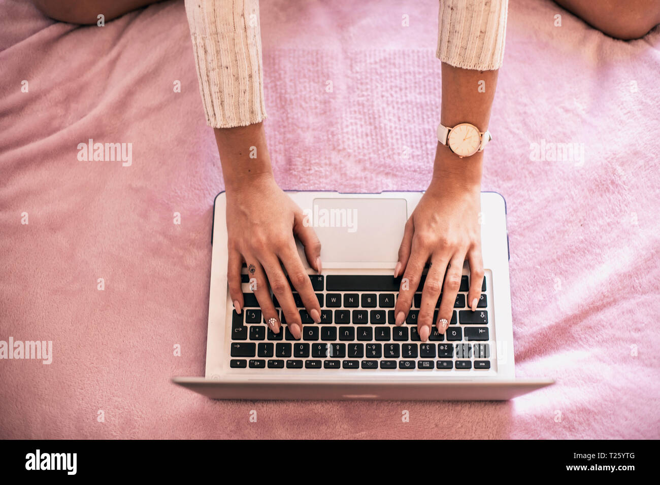 Woman's hand using laptop on bed, top view Stock Photo