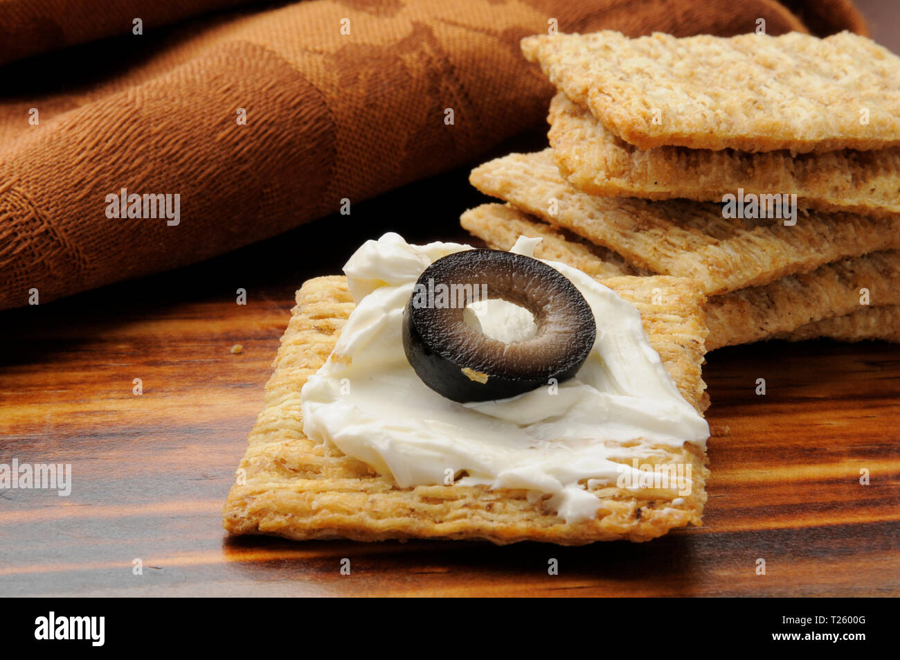 A whole wheat cracker with cream cheese and an olive Stock Photo Alamy