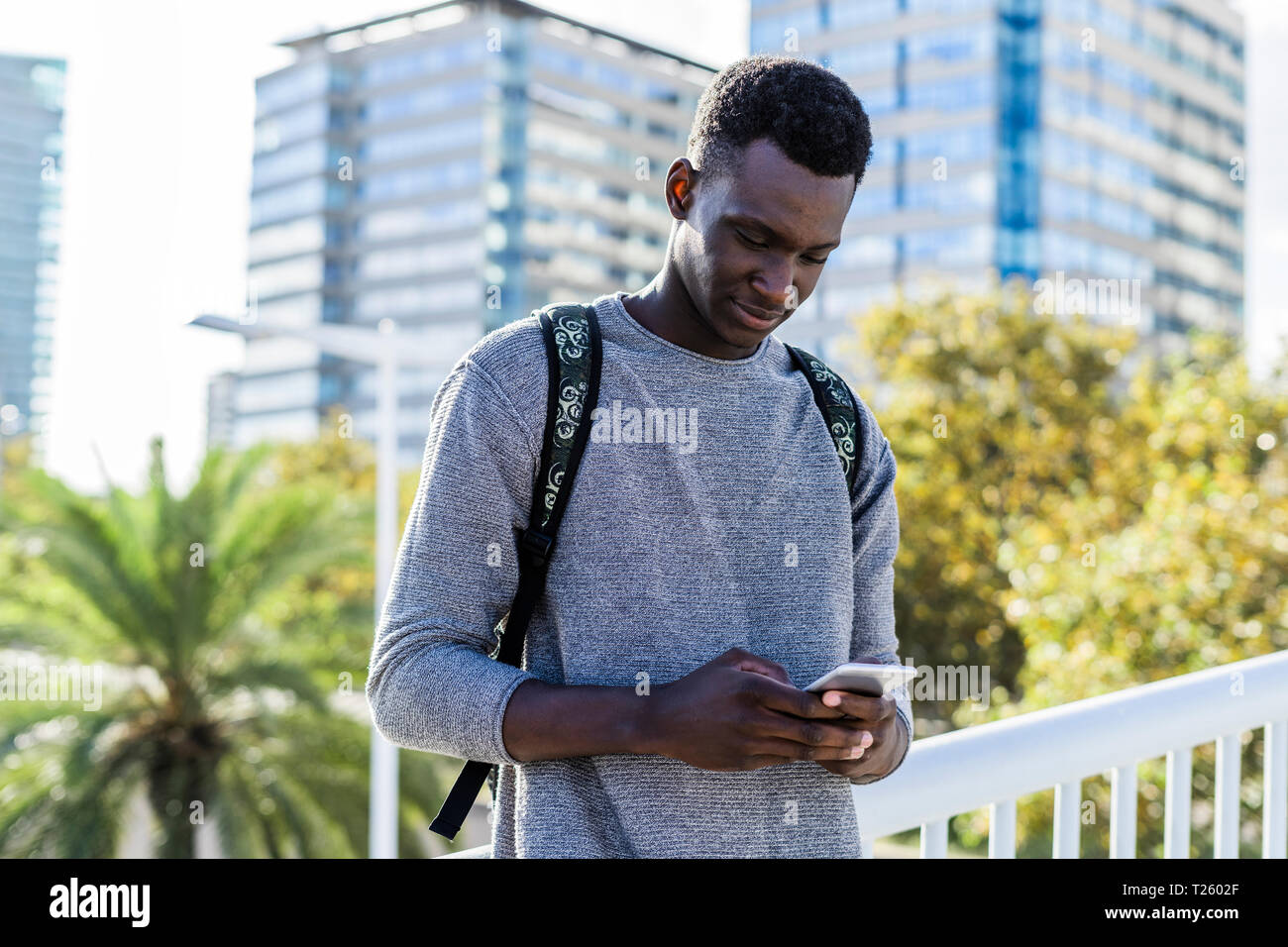 Young man standing on a bridge, using smartphone Stock Photo