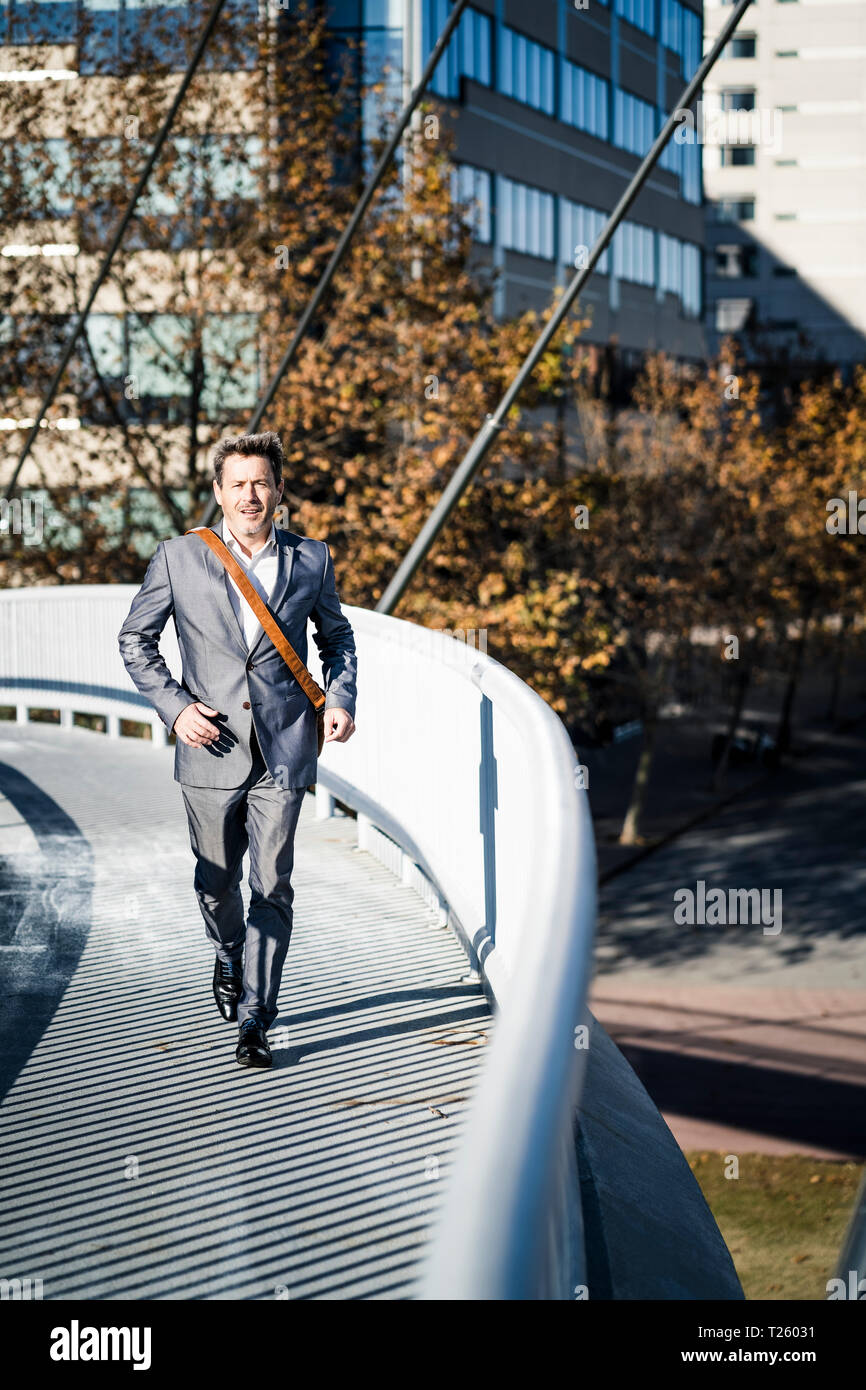 Businessman wearing full suit, running on a bridge Stock Photo Alamy