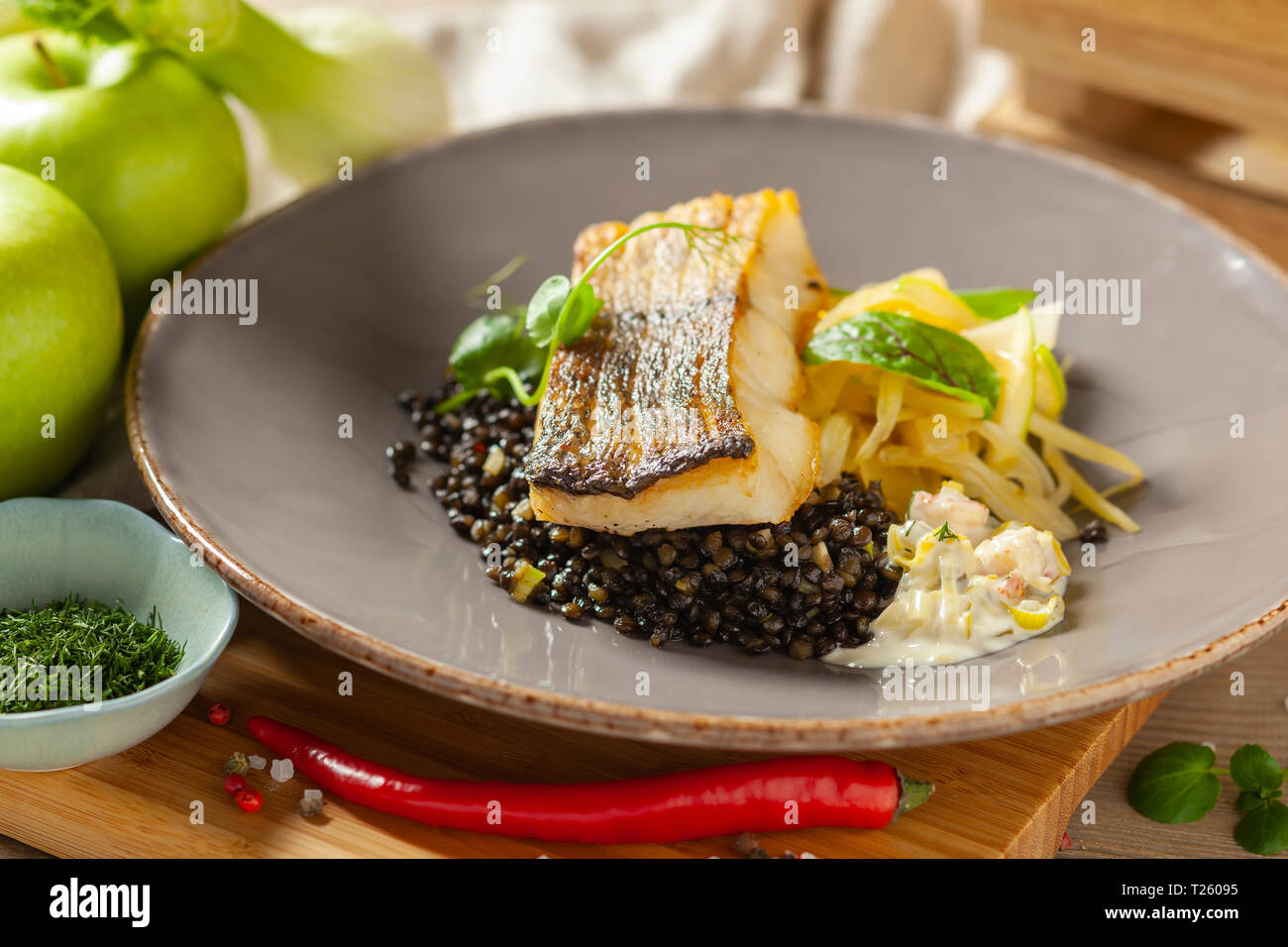 Hake marinated in lemon oil with black lentils with chili and celery, crayfish sauce Stock Photo