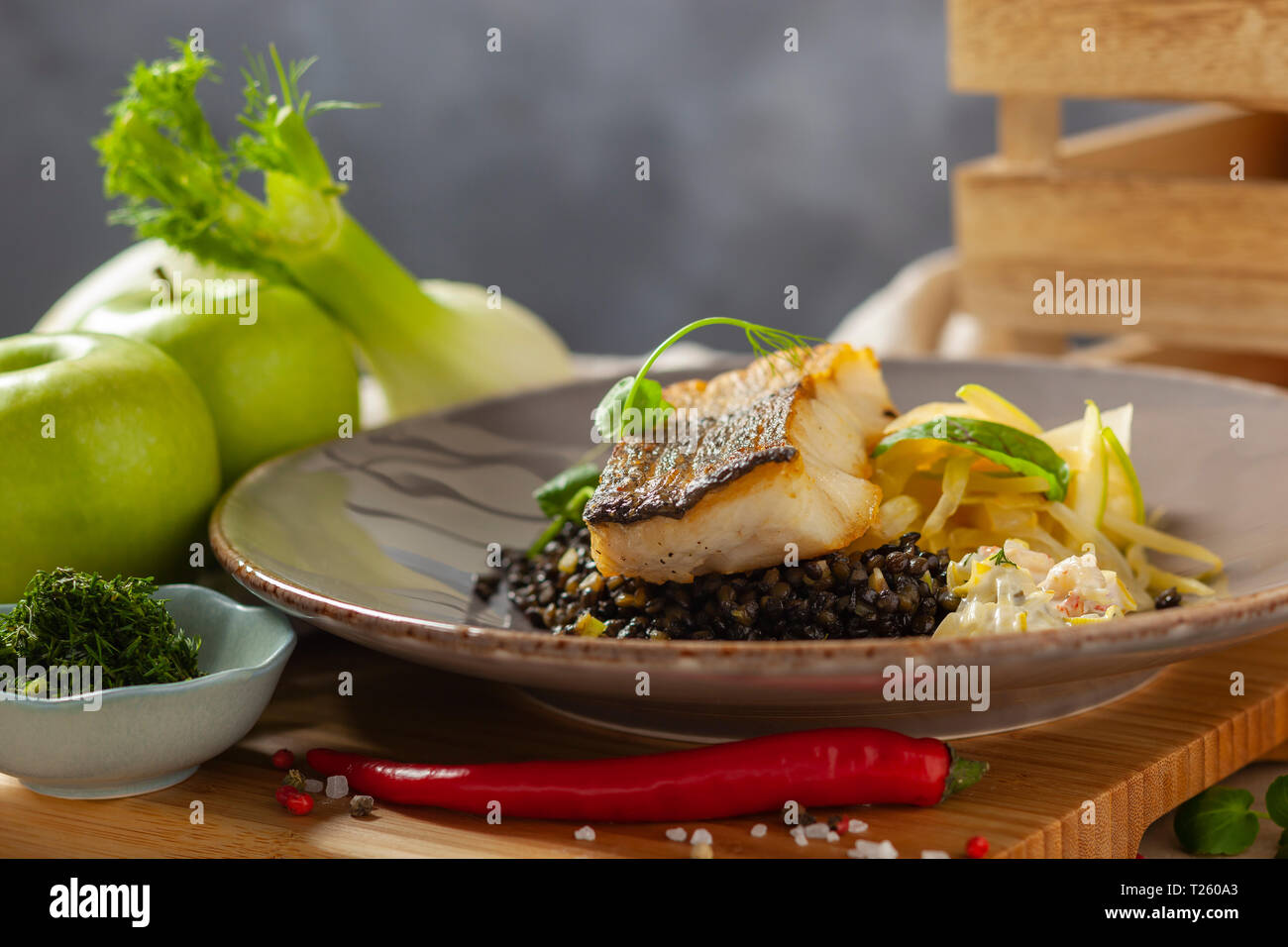 Hake marinated in lemon oil with black lentils with chili and celery, crayfish sauce Stock Photo
