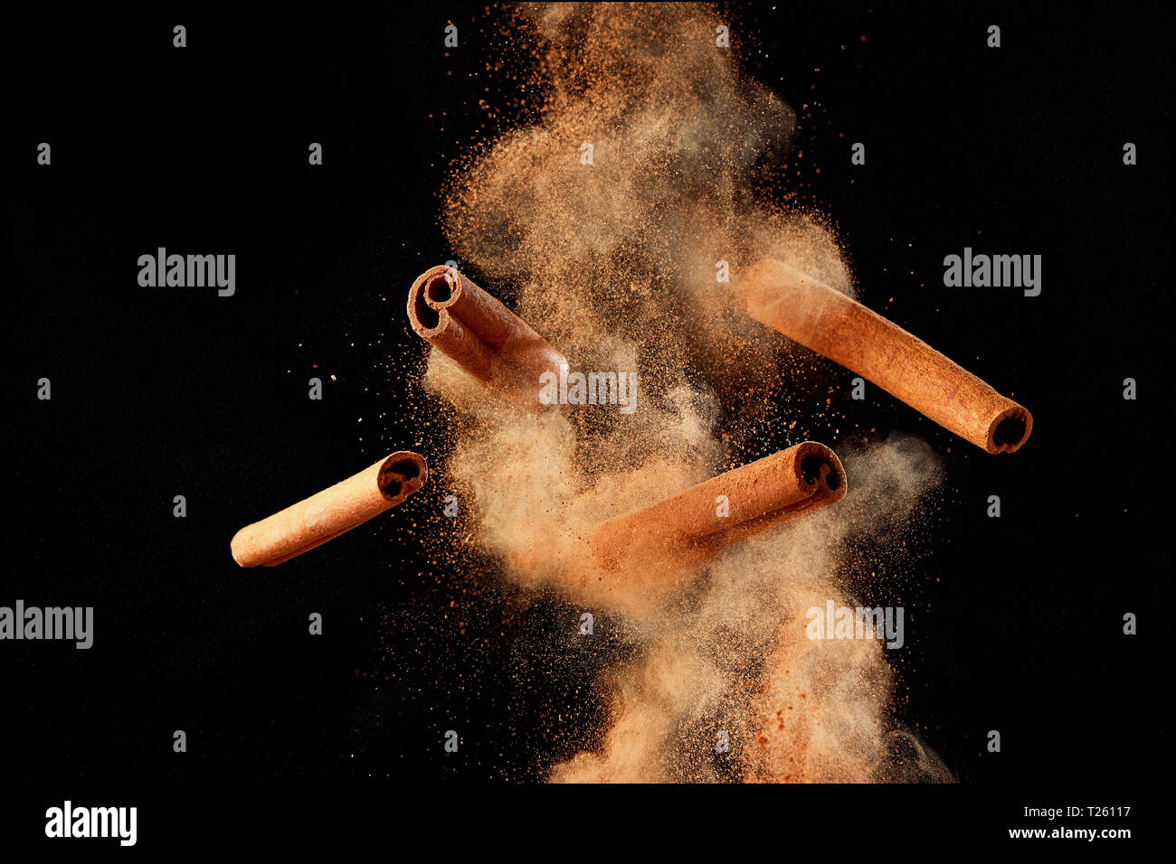 Food explosion with cinnamon sticks and powder, on black background. Stock Photo