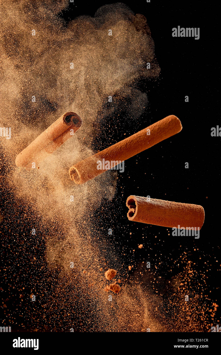 Food explosion with cinnamon sticks and powder, on black background. Stock Photo