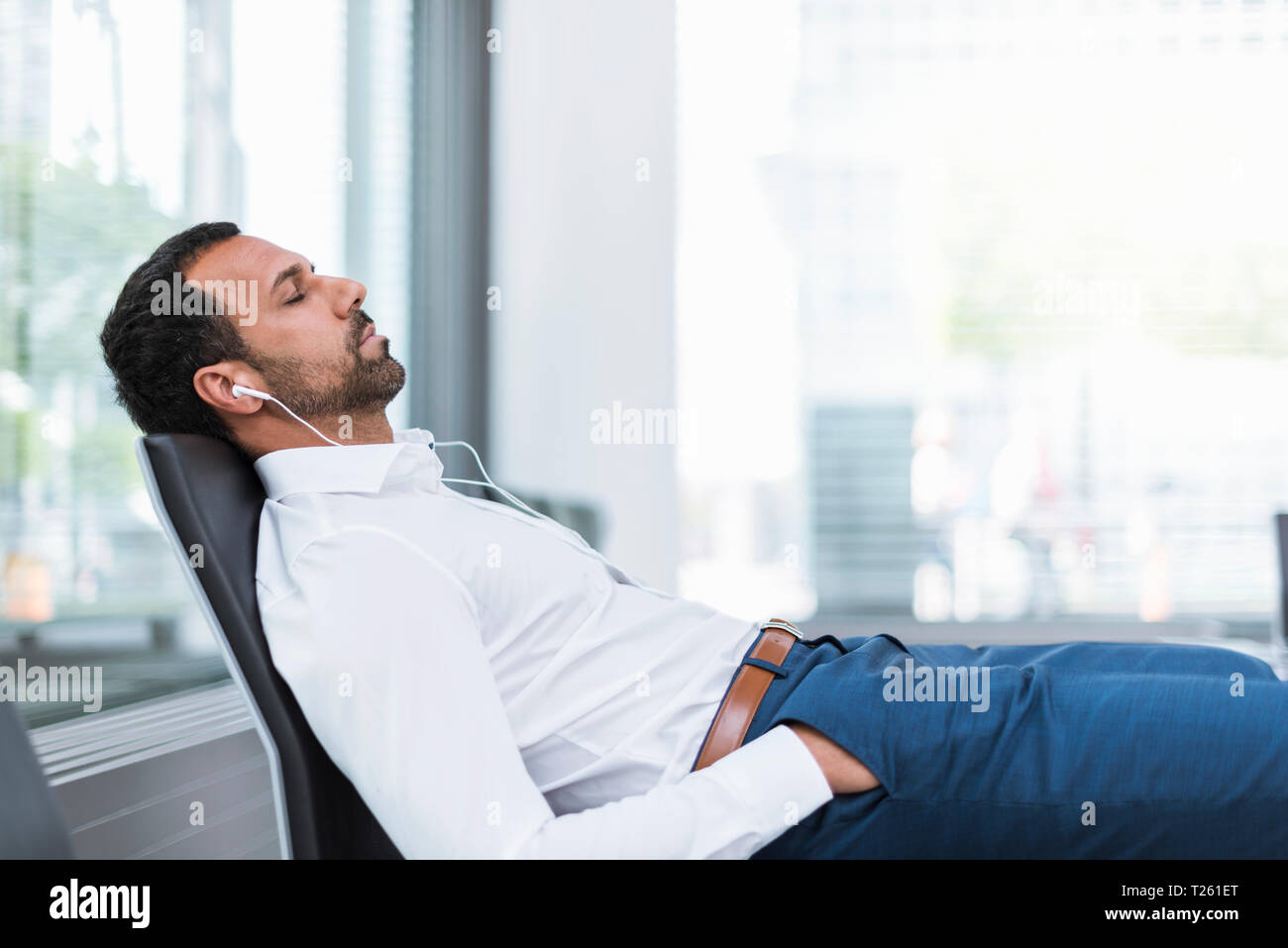 Businessman with earphones, closed eyes Stock Photo