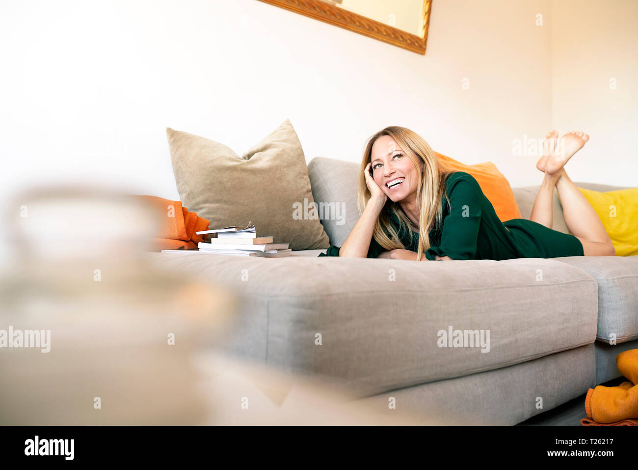 Portrait of laughing woman lying on the couch at home Stock Photo - Alamy