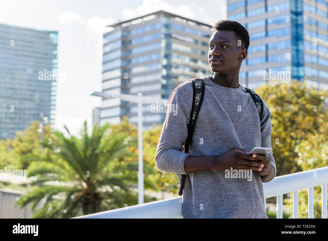 Young man standing on a bridge, using smartphone Stock Photo