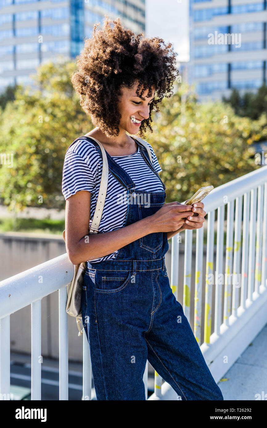 Young woman standing on a bridge, using smartphone Stock Photo