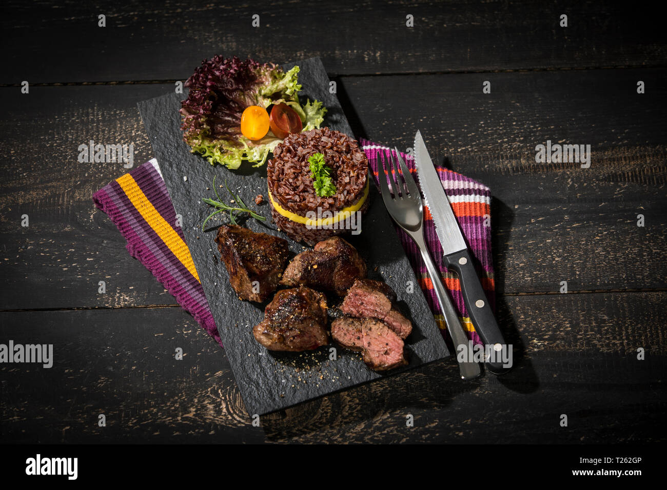 Kangaroo steak with red rice and mango on slate plate Stock Photo