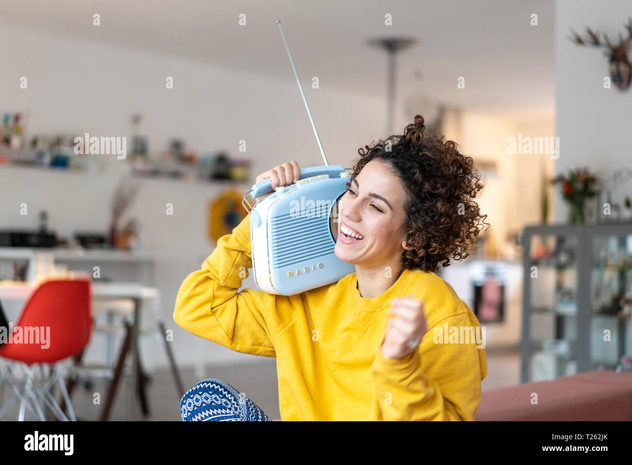 Woman listening to music with portable radio at home Stock Photo