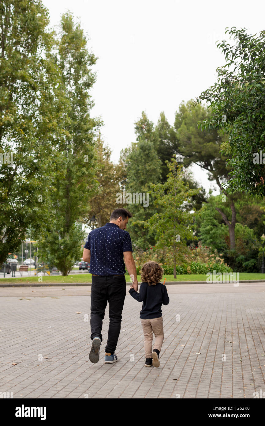 Rear view of father and son walking hand in hand Stock Photo - Alamy