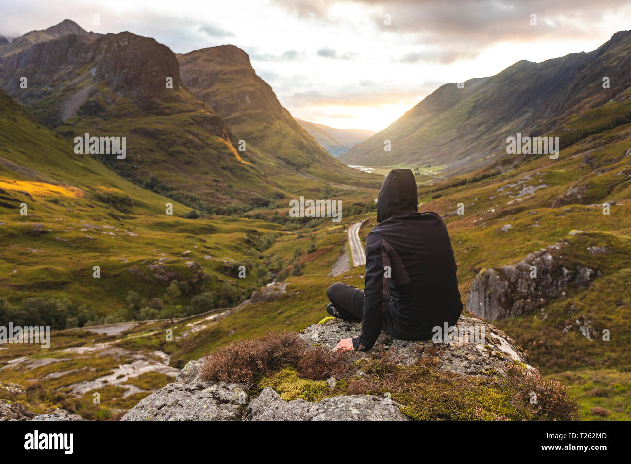 UK, Scotland, Man looking at view with the Three Sisters of Glencoe mountains on the left and the A82 road in the middle of the valley Stock Photo